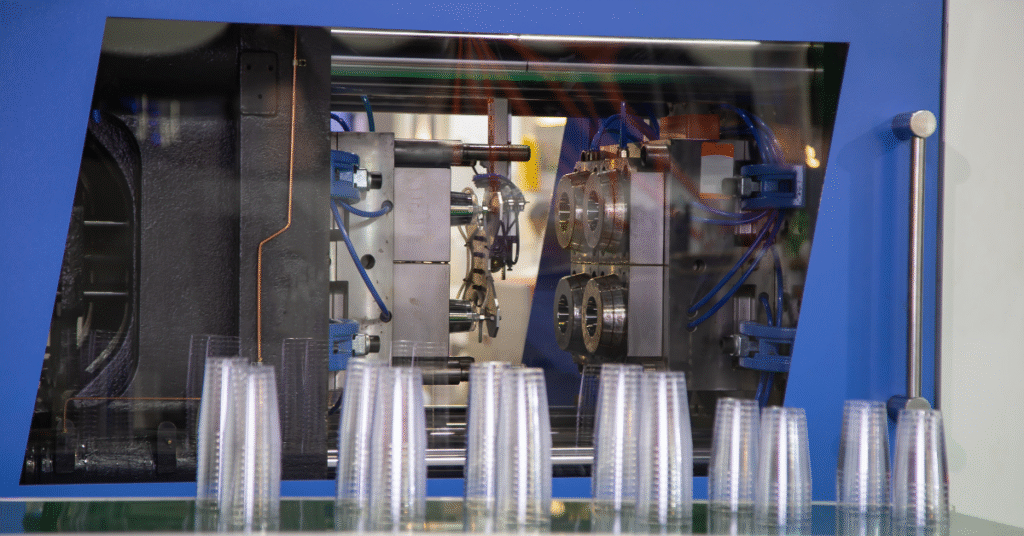 Close-up view of an automated injection molding machine producing plastic cups, demonstrating injection molding speed optimization for high-volume manufacturing.