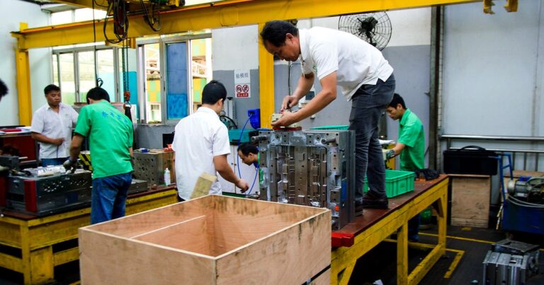 Workers assembling injection mold tooling components at an offshore manufacturing facility